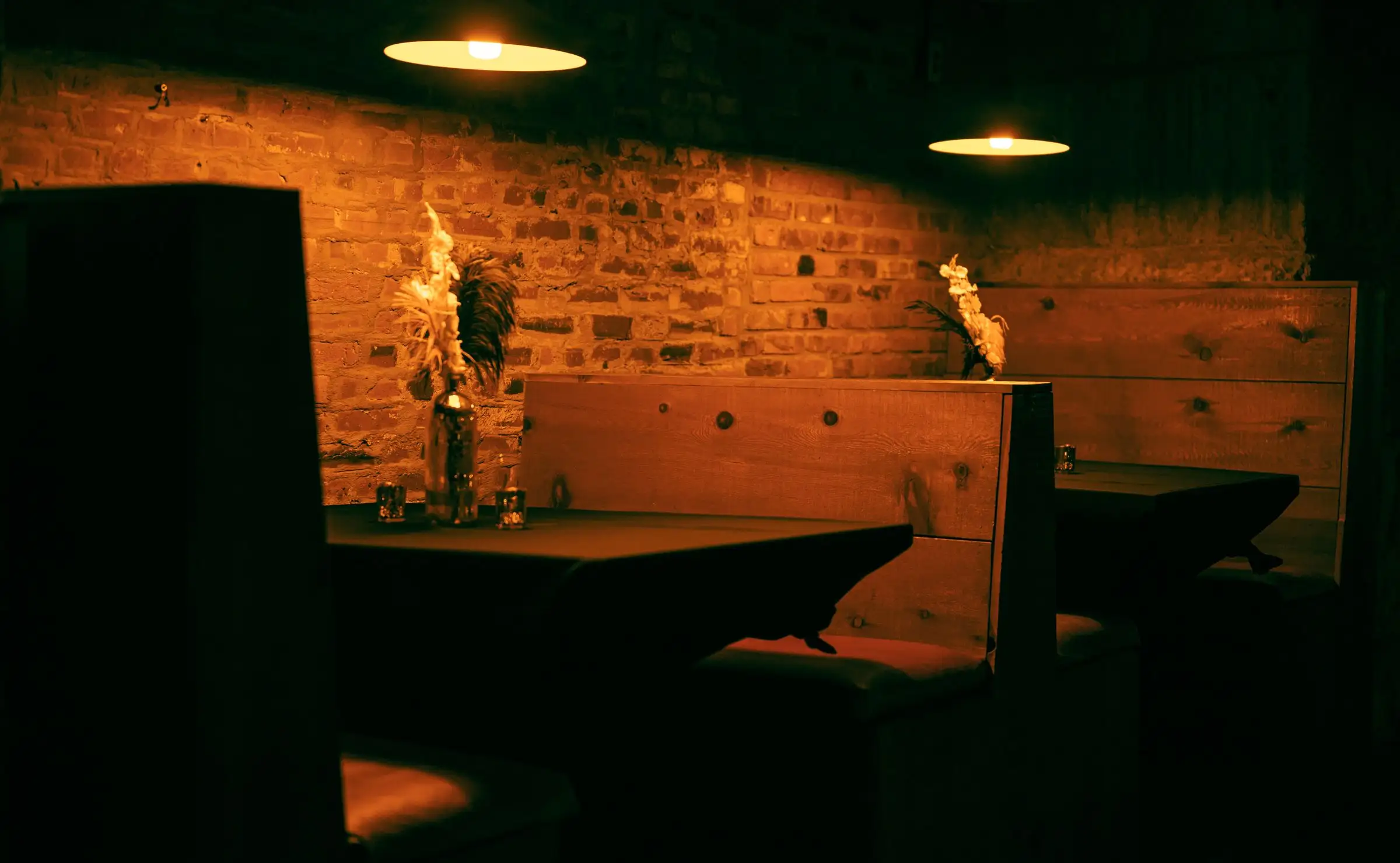 Wooden booths against a brick wall under low, warm pendant lights