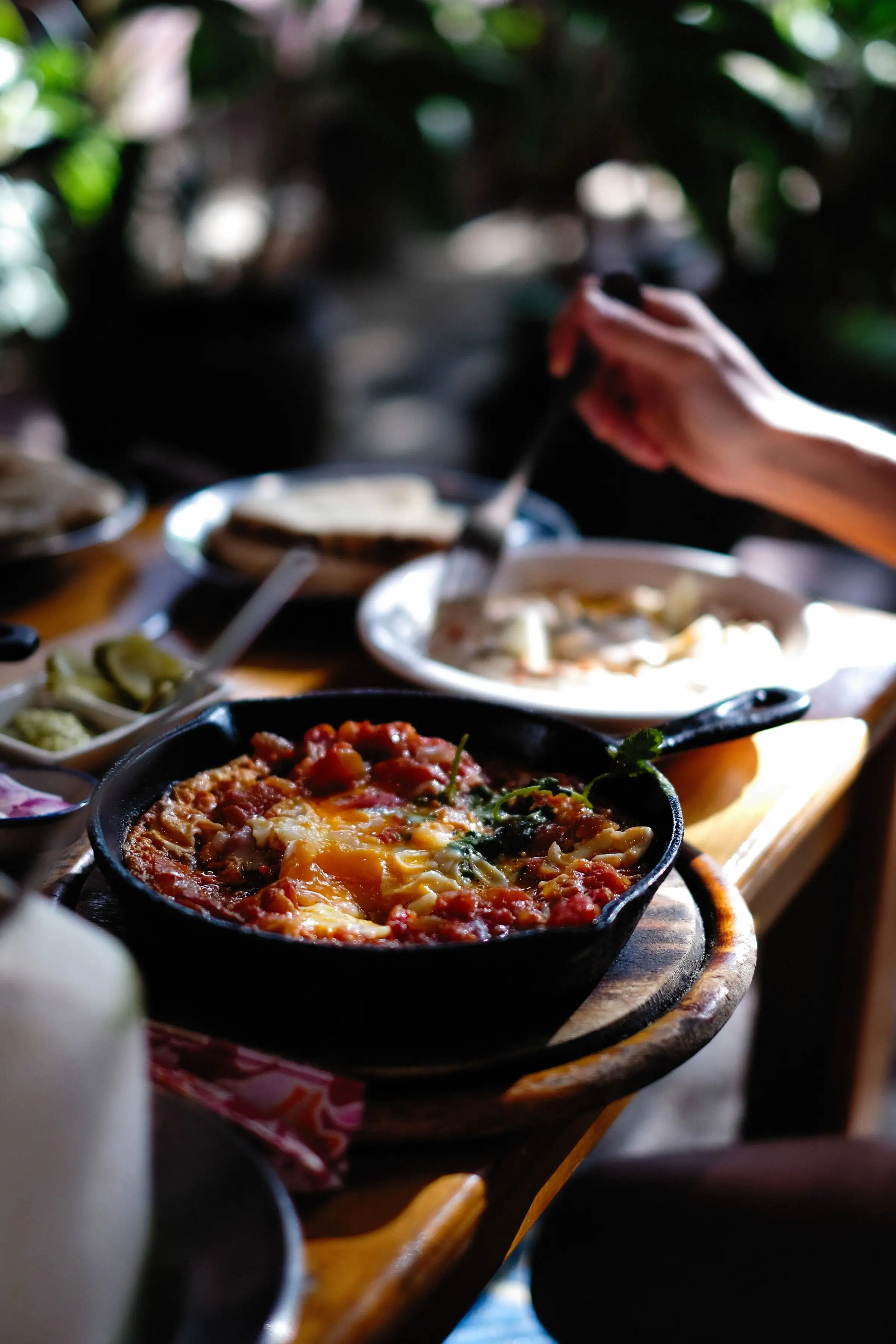 A cast-iron skillet of eggs baked in spiced tomato on a wooden table
