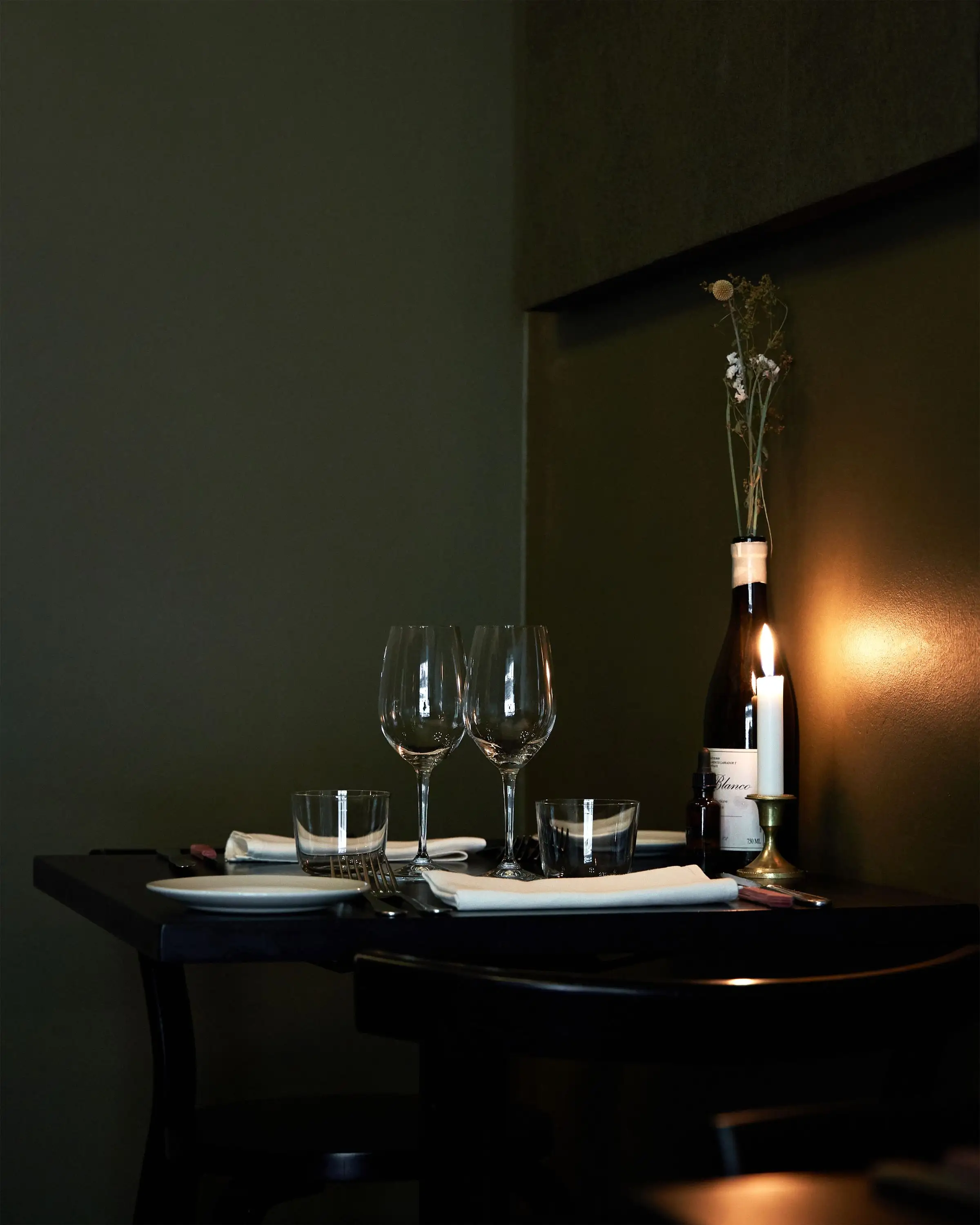A candlelit table set with wine glasses and a bottle, ready for the evening