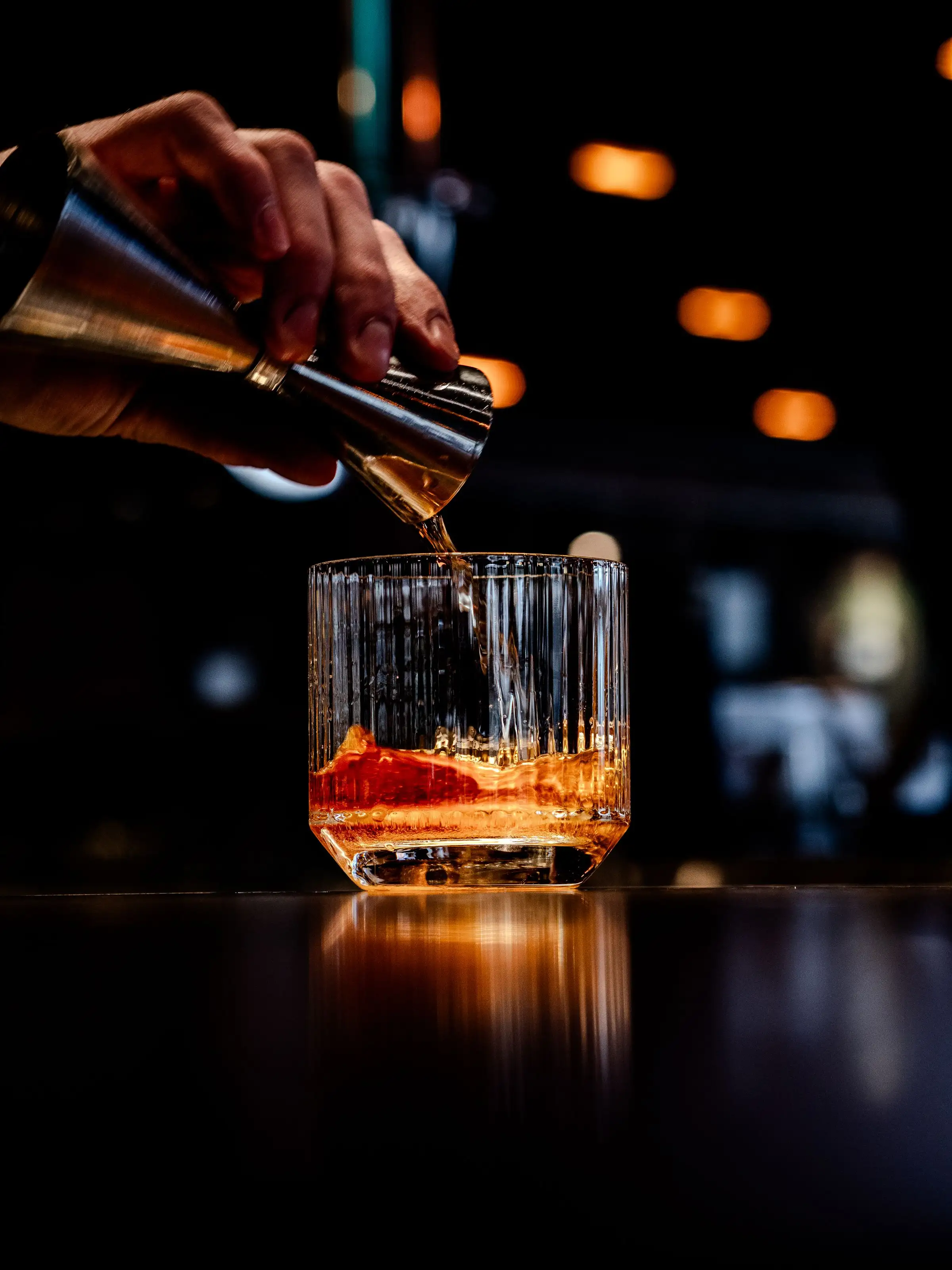 A spirit poured over a large ice cube in a cut-glass tumbler at the bar