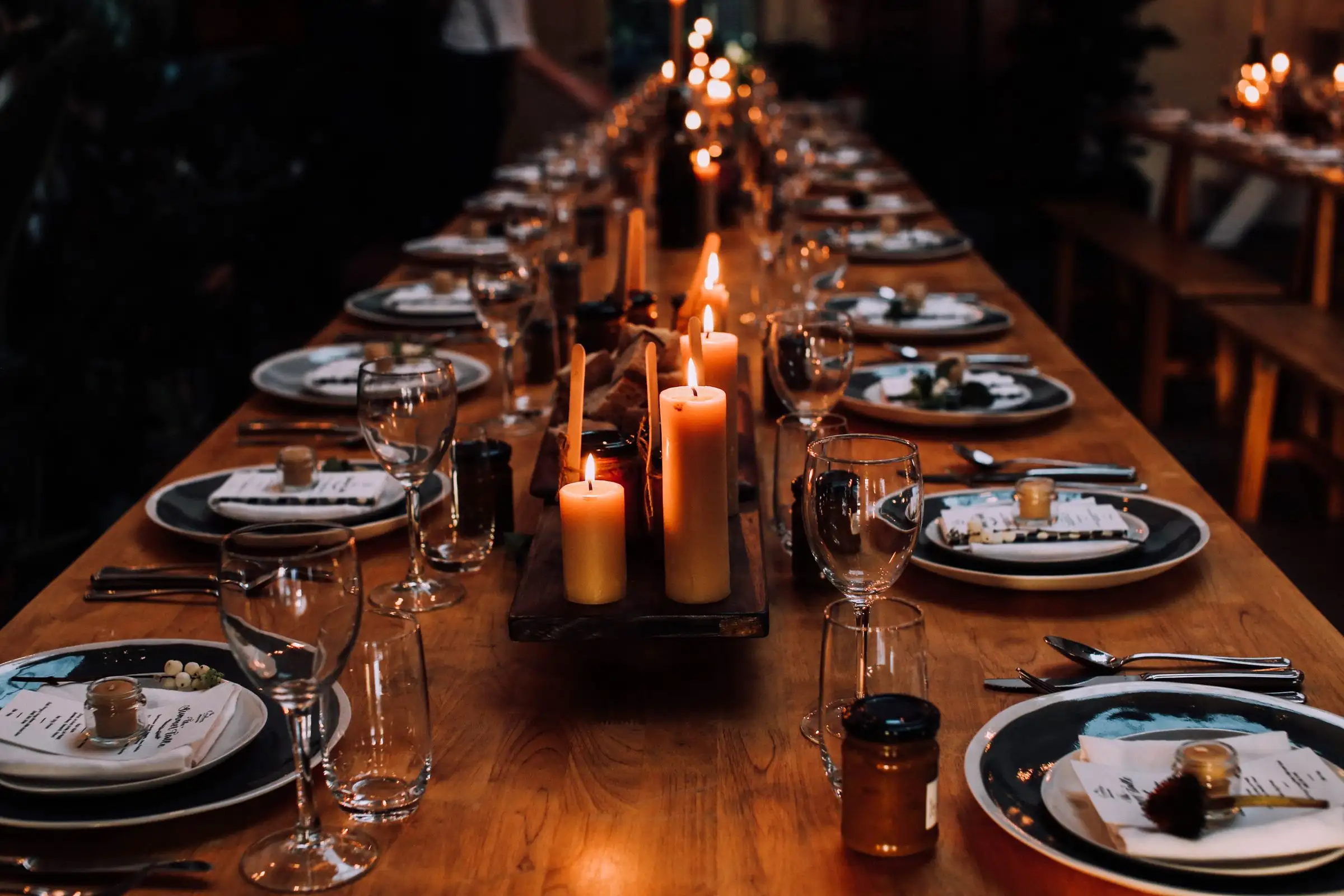 A long table set for a private dinner, lit by rows of candles