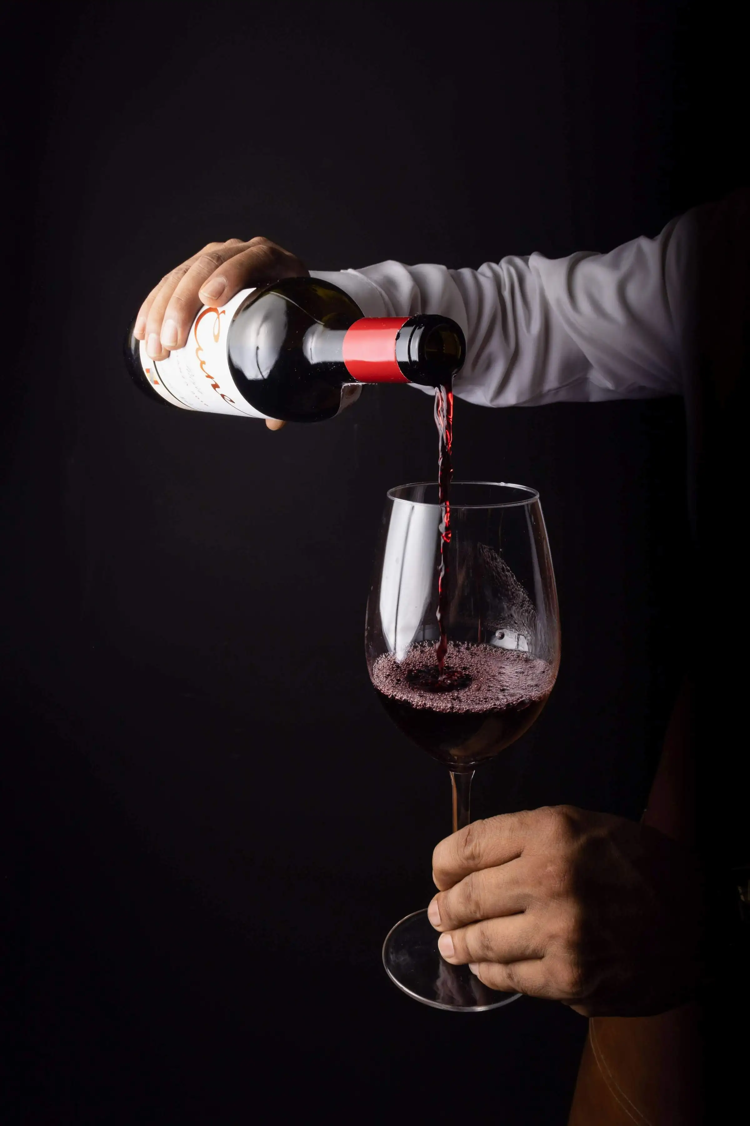Red wine being poured into a glass in low light
